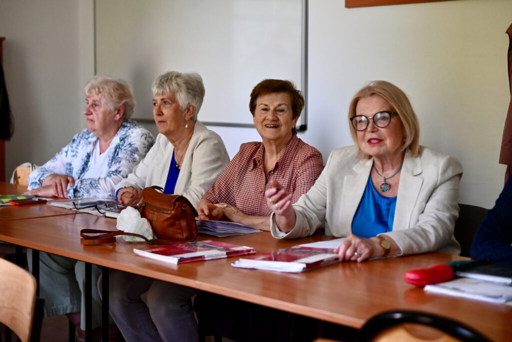 Uniwersytet Trzeciego Wieku UEW - cztery słuchaczki siedzące w sali przy stołach z materiałami dydaktycznymi
